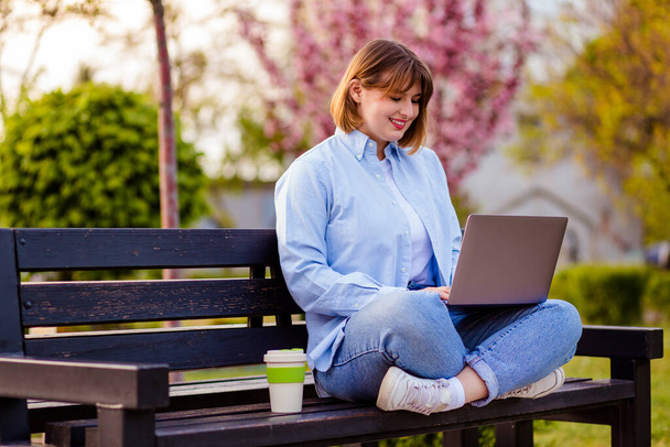 Photo of attractive lady student sit on bench in green park browsing notebook chatting friends do home tasks inspiration nature beauty harmony wear white t-shirt park outdoors - Foto, Imagen