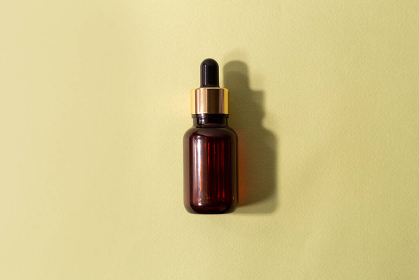 glass brown bottle with pipette with essential oil on a pastel green background top view. Aromatic cosmetic product for skin and hair care Moisturizing beauty product with organic - 写真・画像