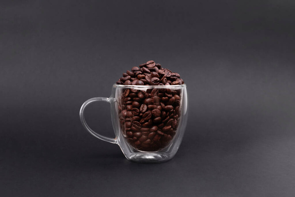 Glass cup full of bean coffee isolated on black background.  Coffee Maker  - Zdjęcie, obraz