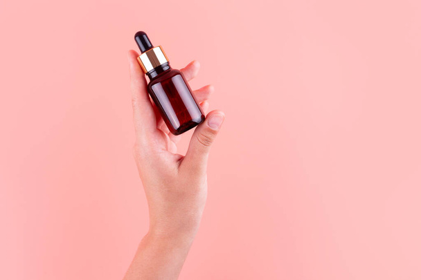 Serum bottle in female hands, top view. Moisturizer for skin care. Nourishing essential oil in glass bottle with pipette. Liquid emulsion with hyaluronic acid. Beauty cosmetic spa product - 写真・画像