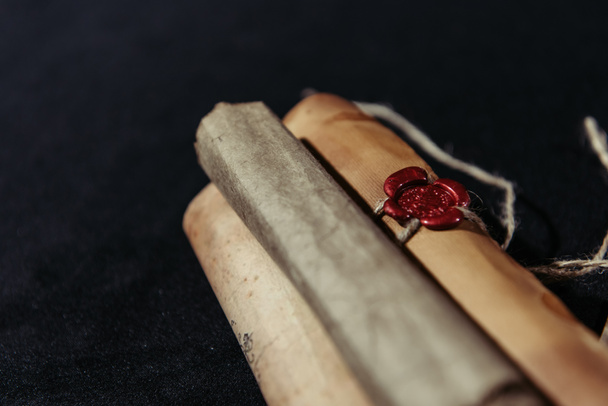 close up view of rolled manuscripts with wax seal on black background - Zdjęcie, obraz