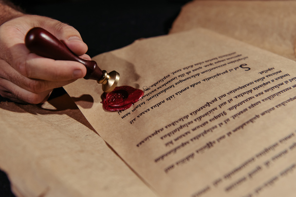 close-up zicht op manuscript met waszegel in de buurt van bijgesneden monnik geïsoleerd op zwart - Foto, afbeelding