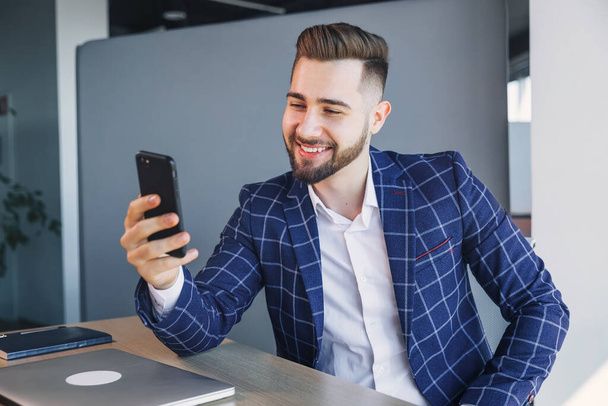 Стильный молодой привлекательный бизнесмен с онлайн видео-звонком в офисе - Фото, изображение