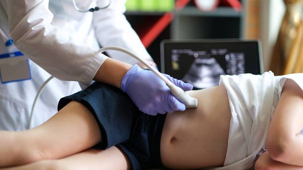 Close-up of doctor making examining with ultrasound of internal organs of child in clinic office. Ultrasound of abdominal cavity procedure concept - Photo, image