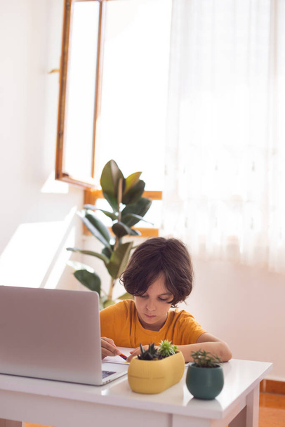 kind jongen is met behulp van een laptop en online studeren met video call leraar thuis, thuisonderwijs, afstandsonderwijs, online onderwijs, kind op online les, afstandsonderwijs - Foto, afbeelding