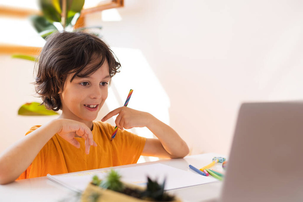 Kind benutzt Laptop und lernt online mit Videoanruflehrer zu Hause, Hausaufgabenbetreuung, Fernunterricht, Online-Bildung, Kind im Online-Unterricht, Fernunterricht - Foto, Bild