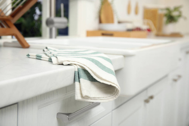Clean towel on white table in kitchen, closeup view - Fotó, kép