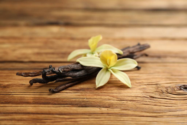 Aromatic vanilla sticks and flowers on wooden table, closeup - Фото, зображення