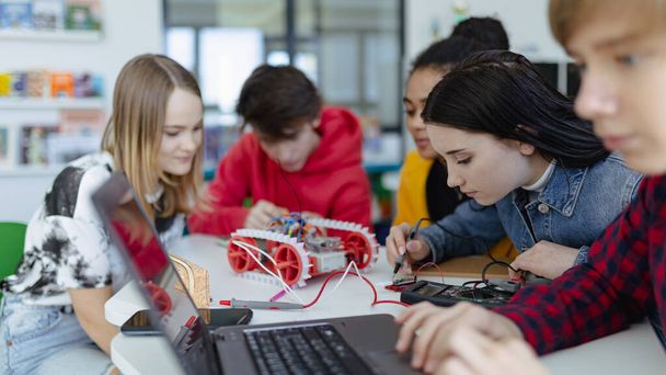Un grupo de estudiantes de secundaria construyendo y programando juguetes eléctricos y robots en el aula de robótica - Foto, imagen