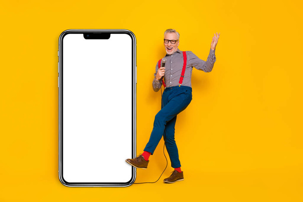 Full length body size view of attractive cheerful grey-haired man singing song copy space isolated over bright yellow color background. - Photo, image
