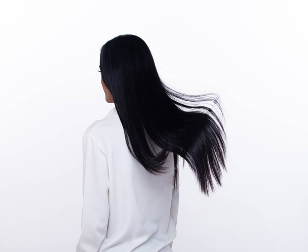 Black Straight Long Black Hair γυναίκα ρίξει μύγα στον αέρα με τη μόδα κομψό και διασκεδαστικό χαρά. Γυναικεία στροφή πίσω φορούν λευκό πουκάμισο εκφράζουν συναίσθημα ευτυχής από φυσούν τα μαλλιά του ανέμου, απομονωμένο λευκό φόντο - Φωτογραφία, εικόνα