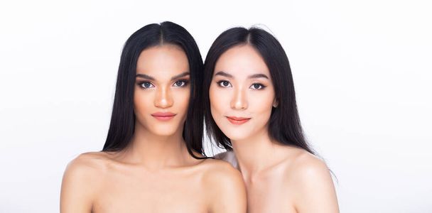 Δύο 2 Όμορφη φρέσκο δέρμα γυναίκες ανοιχτό ώμο με καθαρή εμφάνιση συνθέτουν και μακριά μαύρα μαλλιά. Πορτρέτο νεαρά κορίτσια σε ελκυστικό φυσικό πρόσωπο μόδας εκφράζουν αισθάνονται χαμόγελο, απομονωμένο λευκό φόντο - Φωτογραφία, εικόνα