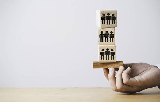 Hand holding and stacking of human icon on wooden cube block for customer focus and customer relationship value concept. - Fotó, kép