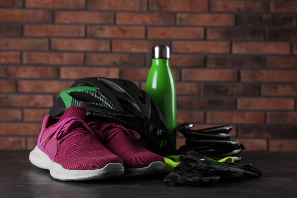 Different cycling accessories on black table against brick wall - Fotografie, Obrázek