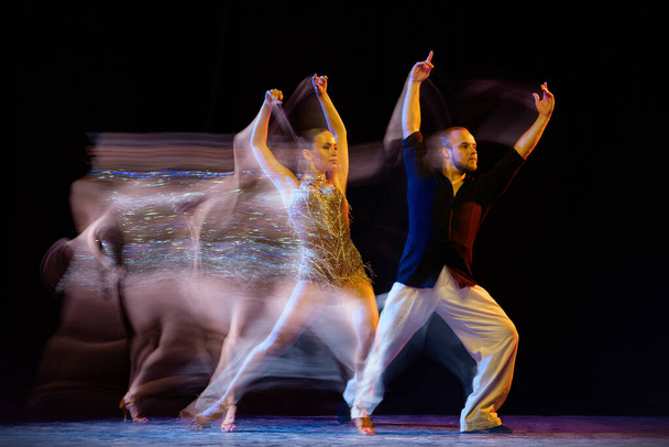 Свободу. Два профессиональных танцора танцуют бальный танец на тёмном фоне со смешанным светом. Концепция искусства, танца, красоты, музыки, стиля. Международный день танца - Фото, изображение