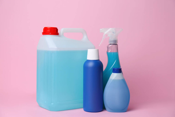 Many bottles of different detergents on pink background. Cleaning supplies - Foto, Bild