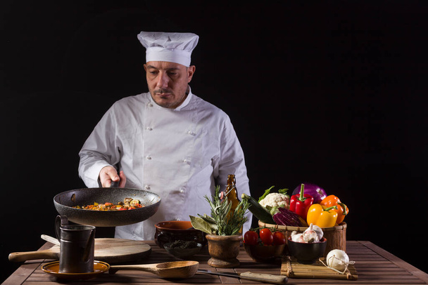 Шеф-кухар у білій формі та капелюсі з виглядом на сковороду перед подачею під час роботи на кухні ресторану
 - Фото, зображення