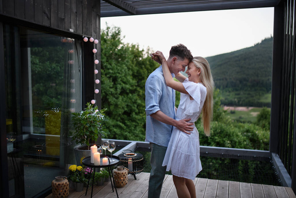 A young couple dancing outdoors, weekend away in tiny house in countryside, travel and holiday concept. - Foto, Imagen