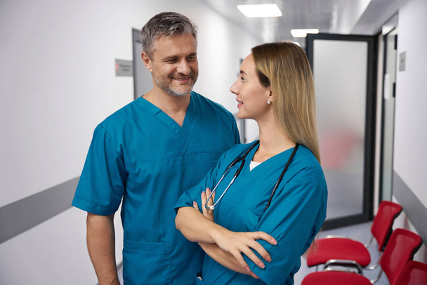 Двоє лікарів дивляться один на одного в яскравому коридорі лікарні
 - Фото, зображення