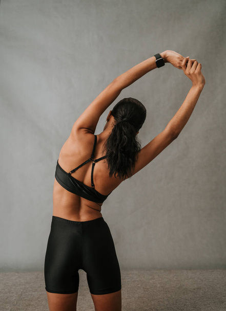 African American female doing a waist stretching exercise with her fit bit watch in her ports wear. High quality photo - Foto, afbeelding