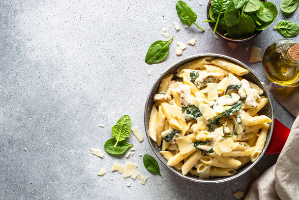 Pasta penne with chicken and spinach in creamy sauce, top view. - Foto, afbeelding