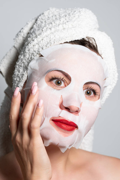 Fabric refreshing face mask, skin care, portrait of a woman with a mask on her face. - Valokuva, kuva