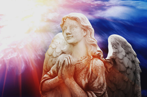 Beautiful angel with wings looking up at the sky in rays of light. Ancient statue. Horizontal image. - Foto, Imagem