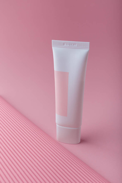 Cosmetics mock up on pink paper background. Cream tube template with no brand. Tender face skin care. Place for text, vertical shot - Foto, Bild