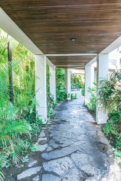 A rock sidewalk wood plank covered pathway or walkway with lush tropical plants overgrown on the sides. - Foto, immagini