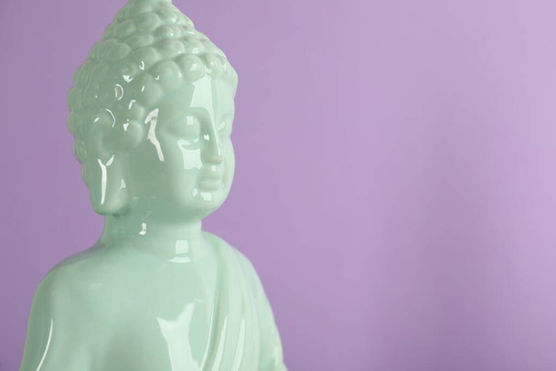 Beautiful ceramic Buddha sculpture on violet background. Space for text - Valokuva, kuva