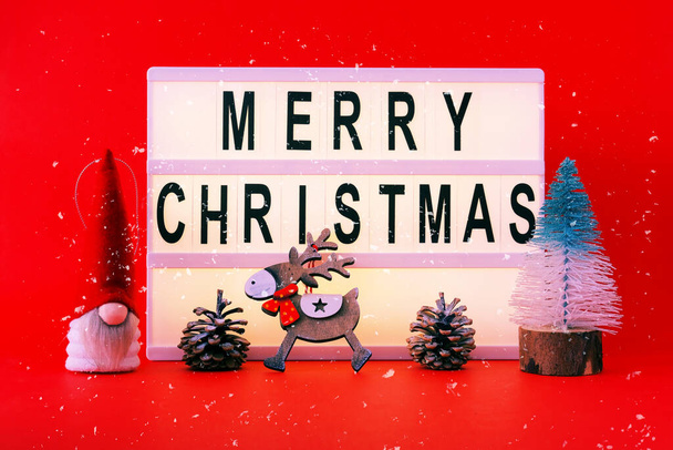 Χριστουγεννιάτικα στολίδια σε κόκκινο φόντο. Καλά Χριστούγεννα σε ελαφρύ κουτί. Χριστουγεννιάτικη διακόσμηση ή στυλ hygge. Δημιουργικός χώρος αντιγράφων για εποχιακά έργα, κοντινό πλάνο - Φωτογραφία, εικόνα