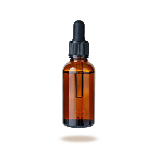 Dark brown glass bottle of face serum or essential oil or pharmaceutical tincture flying isolated on white background - Photo, Image