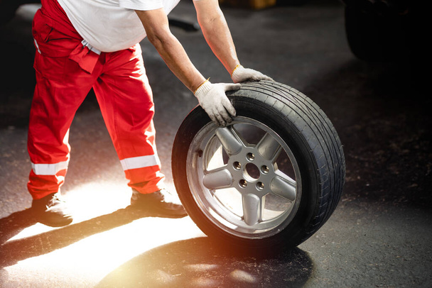 mechanic with car tire wheel for replace. tyre change in garage auto service center - Foto, immagini