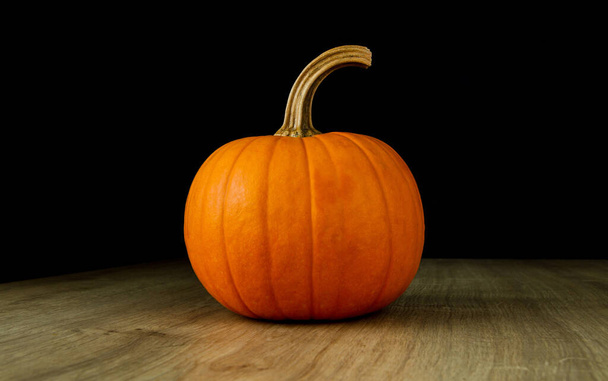 Small decorative autumn pumpkin on a wooden table. - Fotó, kép