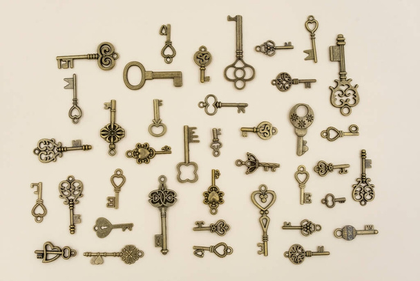 various size and type of Bronze ornamental keys for clocks and treasure boxes arranging at 90 degree angles from each other on pink paper background - Foto, imagen