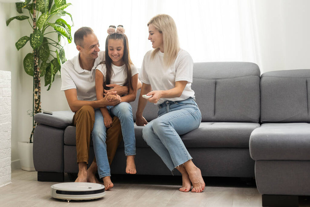 Smiling family pointing at robotic vacuum cleaner. - Foto, afbeelding