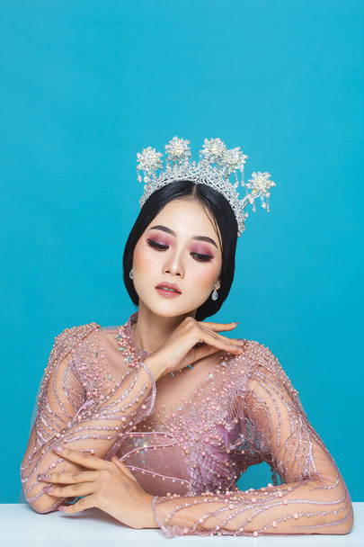 Portrait of asian woman in beautiful makeup wearing pink wedding dress, isolated on blue background. - 写真・画像