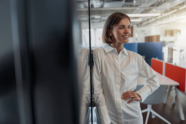 Portrait of attractive european business woman standing in modern office and looking at side - Foto, Bild