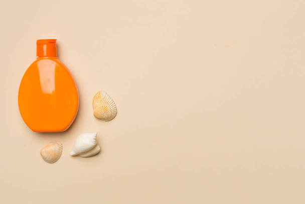 Bottle with sun protection cream and sea shells on color background, top view. - 写真・画像
