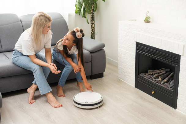 daughter and mother, robot vacuum cleaner, smart home technology. - Photo, image