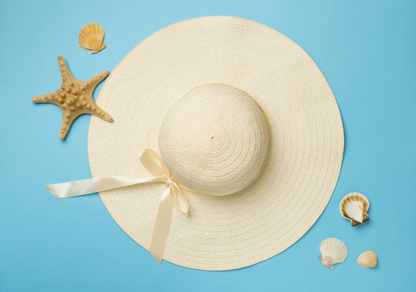 Beautiful straw hat and seashells on color background, top view. - Foto, afbeelding