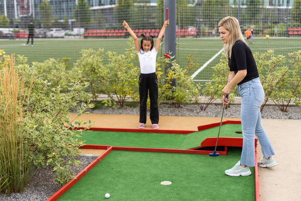 little girl and mother playing mini golf. - Zdjęcie, obraz