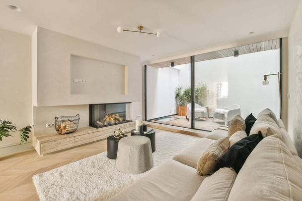 Большой мягкий бархатный диван с красочными подушками в гостиной с деревянным паркетом и кухонным островом под потолком с балками - Фото, изображение