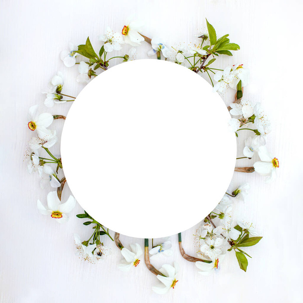 Round frame with spring flowers. fresh cherry blossoms, violets and white daffodils in the form of wreath on wooden background. - Foto, Bild