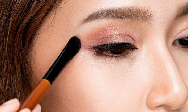 Closeup ardent young woman with healthy fair skin applying her eyeshadow with brush. Female model with fashion makeup. Beauty and makeup concept. - Foto, afbeelding