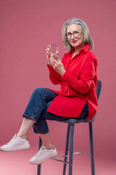 New trend. Mature woman holding eyeshadows palette in hands and smiling - Fotografie, Obrázek