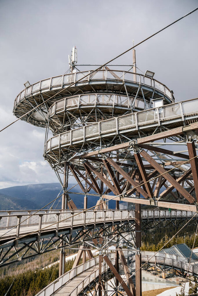 Dolni Morava, Czech Republic, 16 April 2022: Path in the clouds, tourist attraction with spiral platform to observation tower, landscape with forest and sky on mountains, Skywalk with snow - Foto, Bild