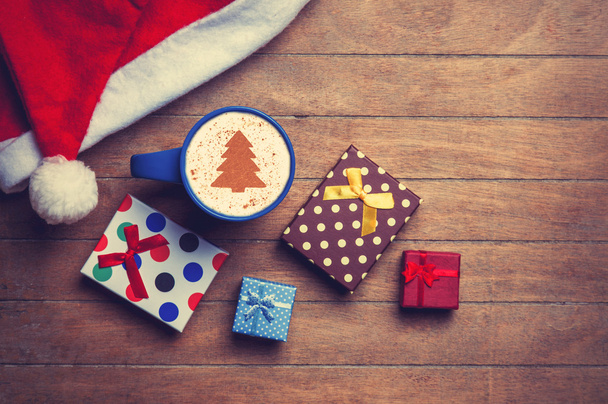 Cappuccino avec chapeau de Noël et cadeau sur table en bois
. - Photo, image