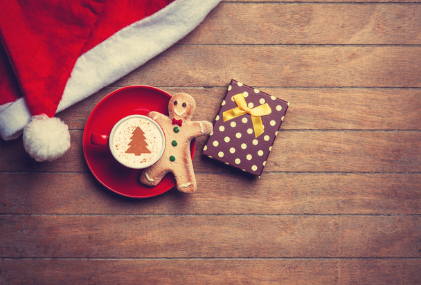 Капучино с рождественской шляпой и пряничным человечком на деревянной доске
 - Фото, изображение