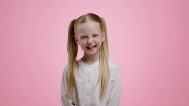 Sincere kid happiness. Adorable little girl with two ponytails laughing loud, pink studio background, slow motion - Footage, Video
